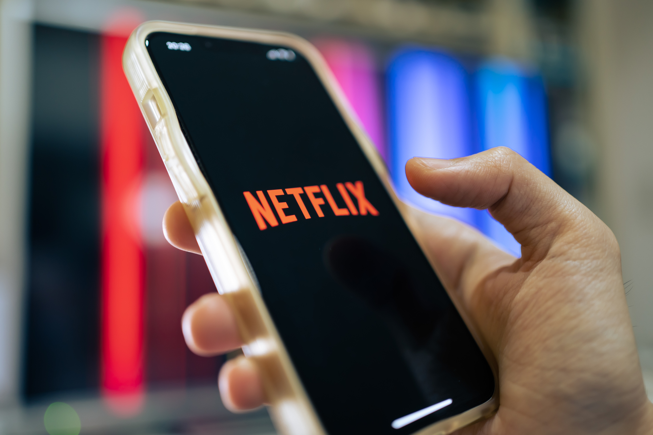 Hand holding a mobile with the Netflix logo on the screen