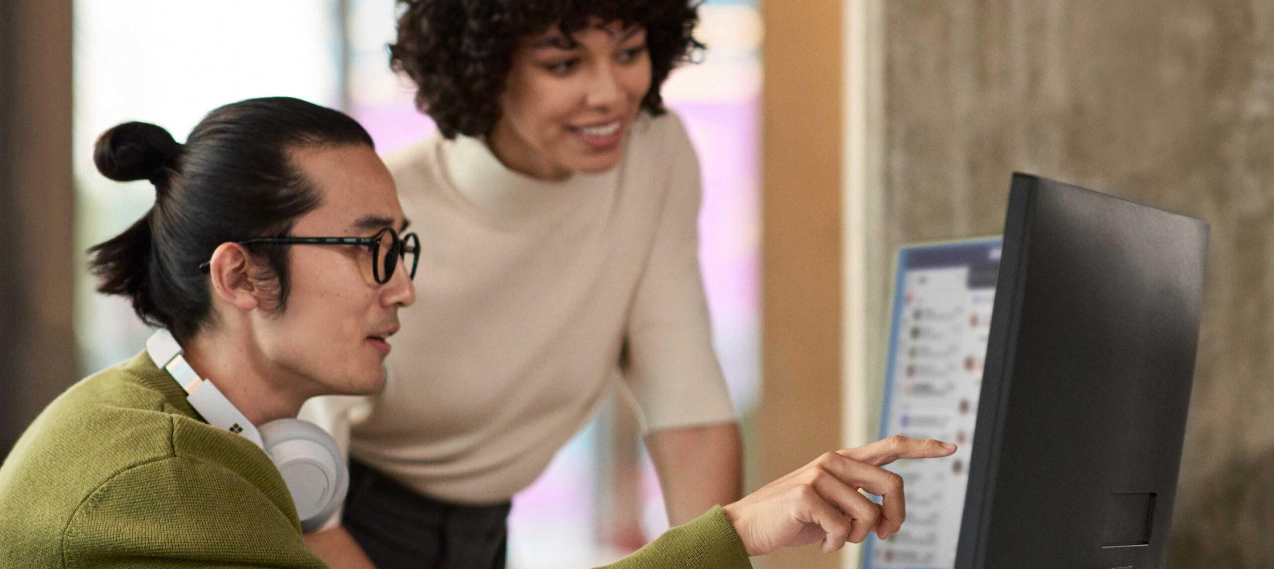 Photo of a 2 colleagues looking at a computer screen together.